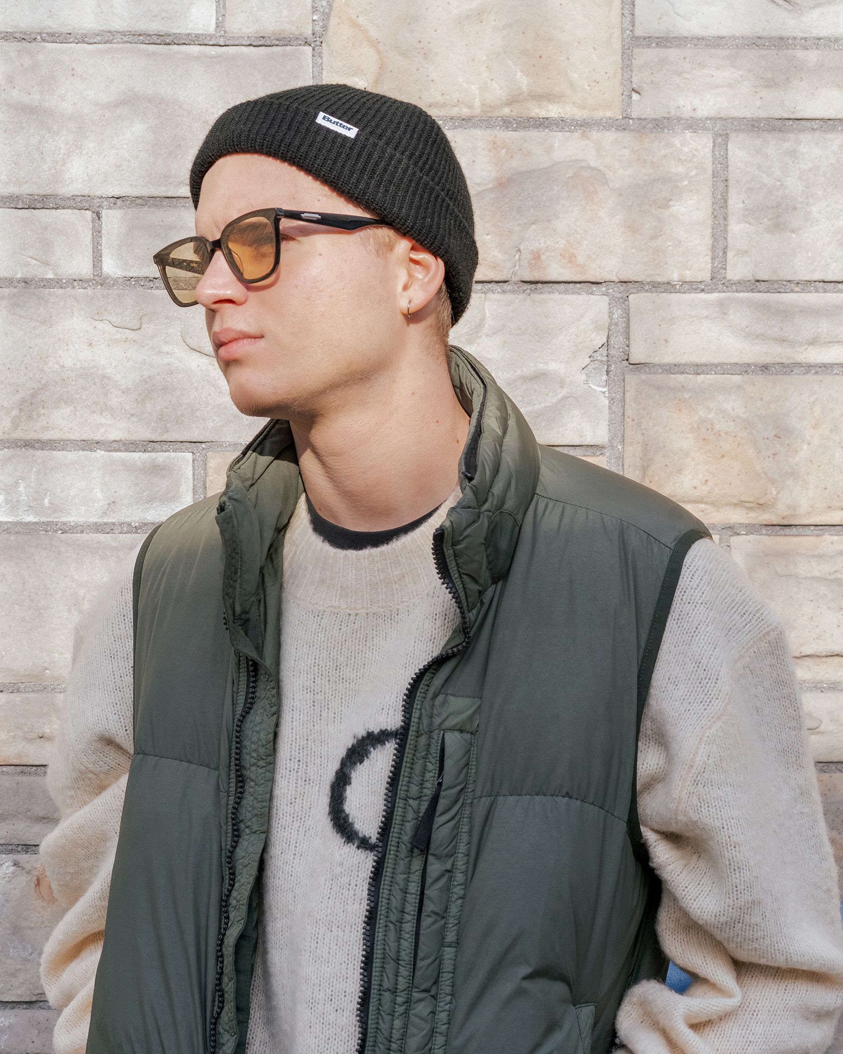 Artysta ustawiony jest lewym profilem do obiektywu. Ma na sobie czapkę, okulary przeciwsłoneczne.