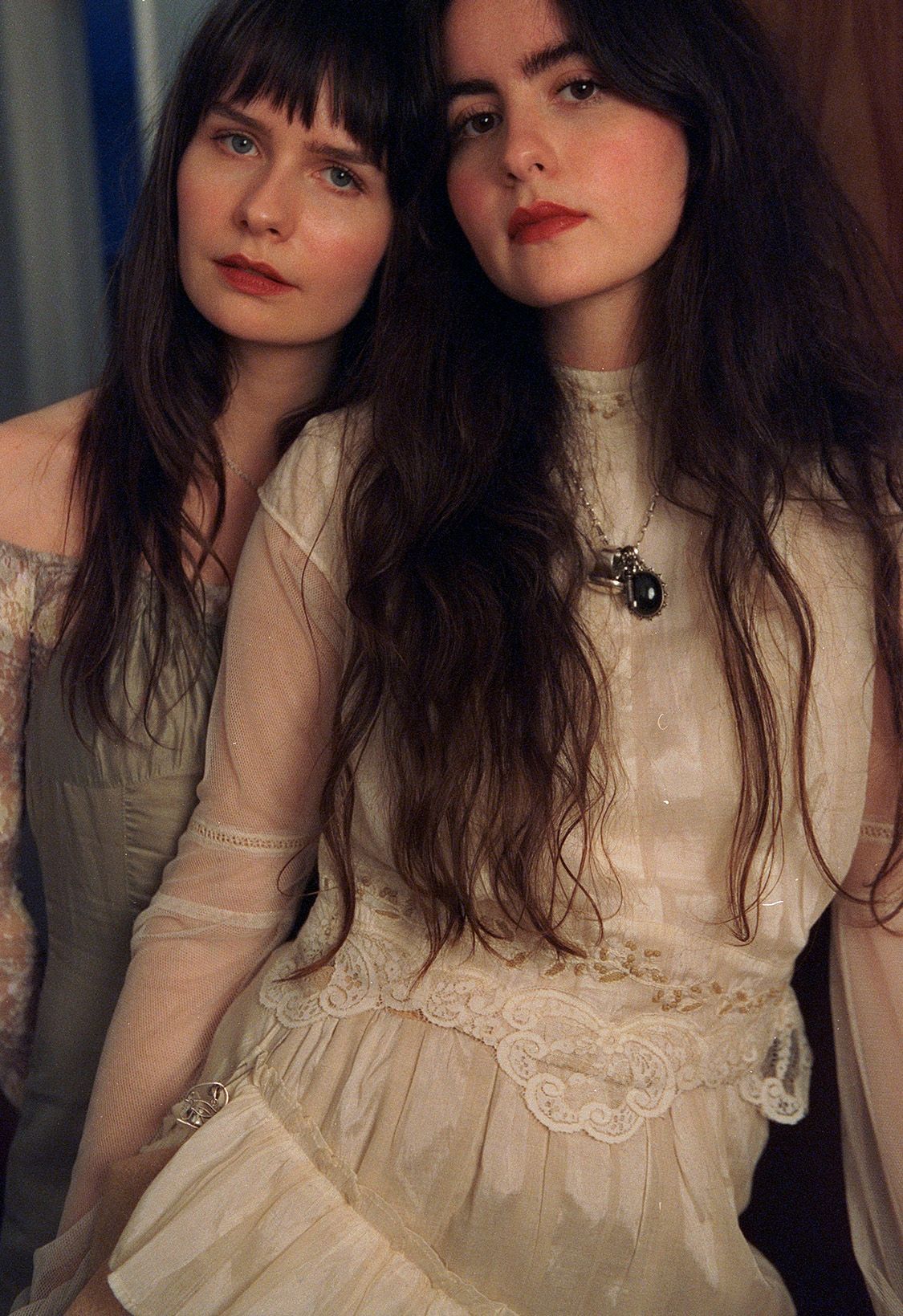 Duet ma na sobie białe, koronkowe sukienki. Artystki opierają się o siebie i patrzą prosto w obiektyw.