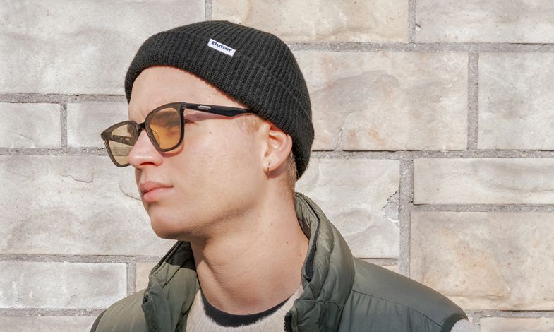 Artysta ustawiony jest lewym profilem do obiektywu. Ma na sobie czapkę, okulary przeciwsłoneczne.